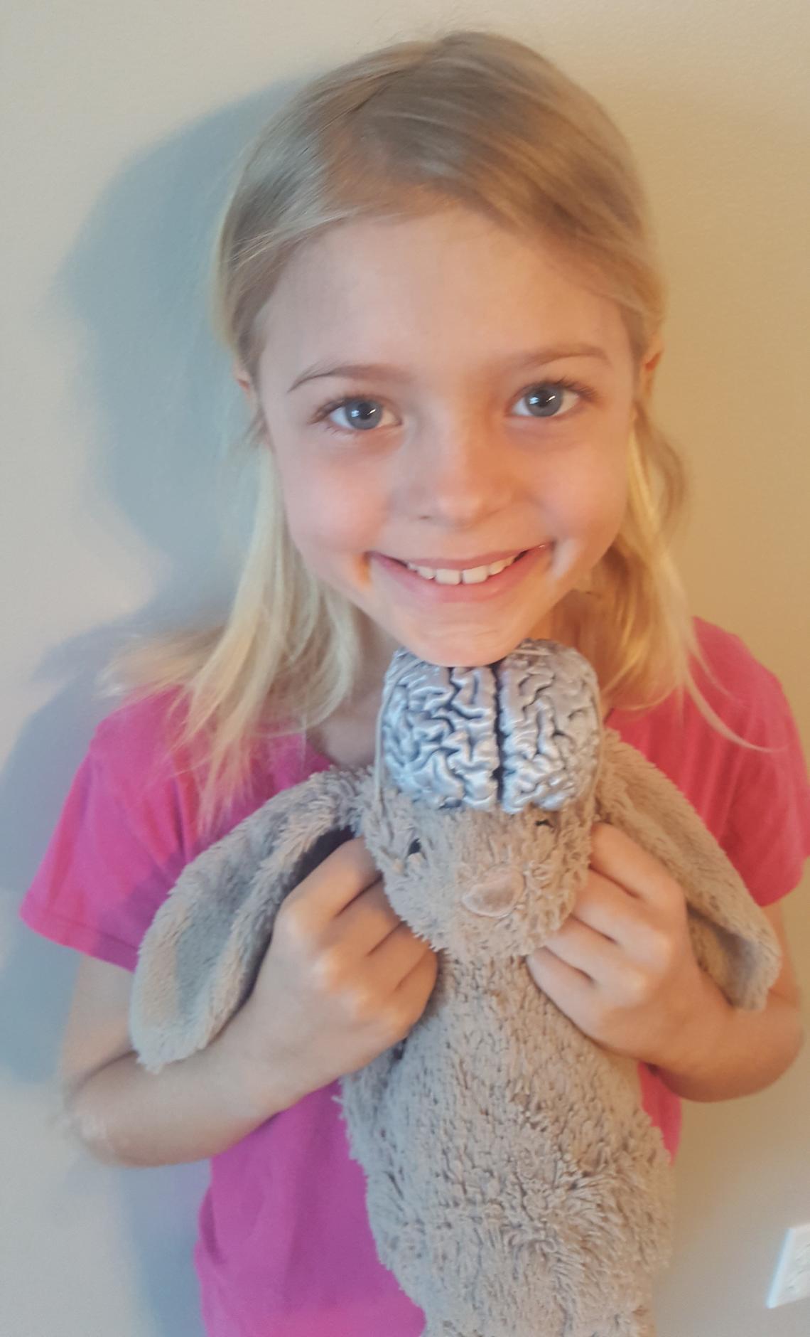 Olivia Mueller, age seven, loves to play with her favourite toy — a plastic model of her own brain that she attaches to her toy bunny.