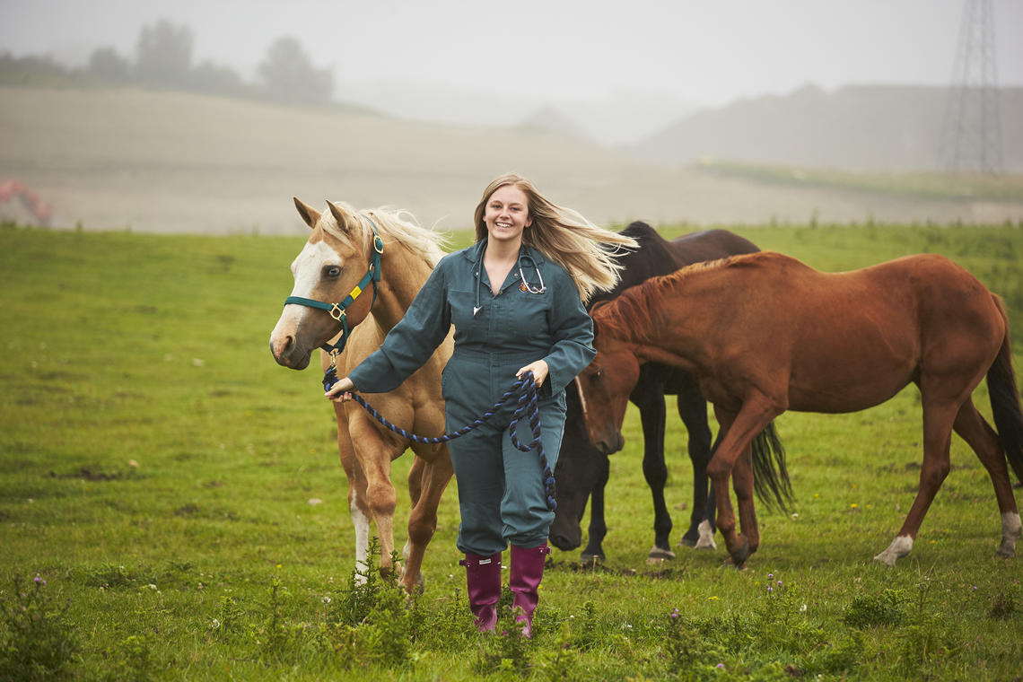 Woman leads horse in pasture