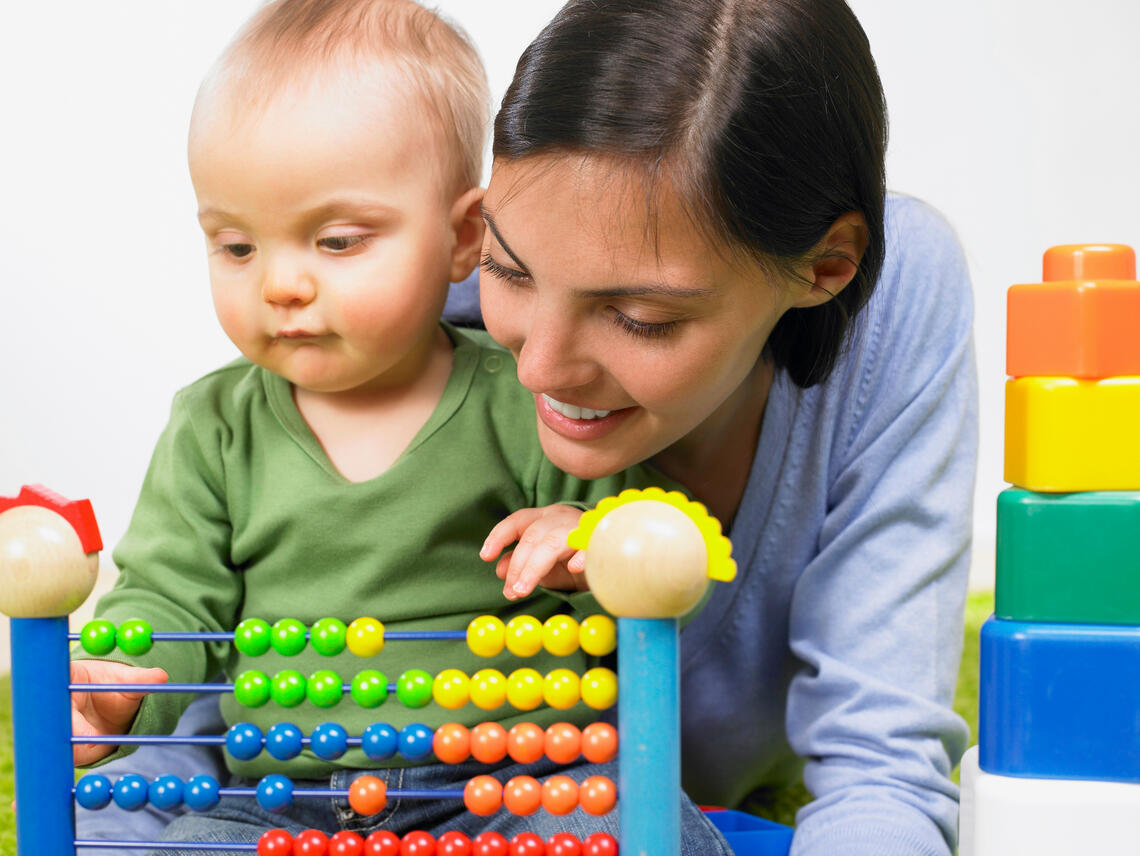 Mother plays with baby and abacus