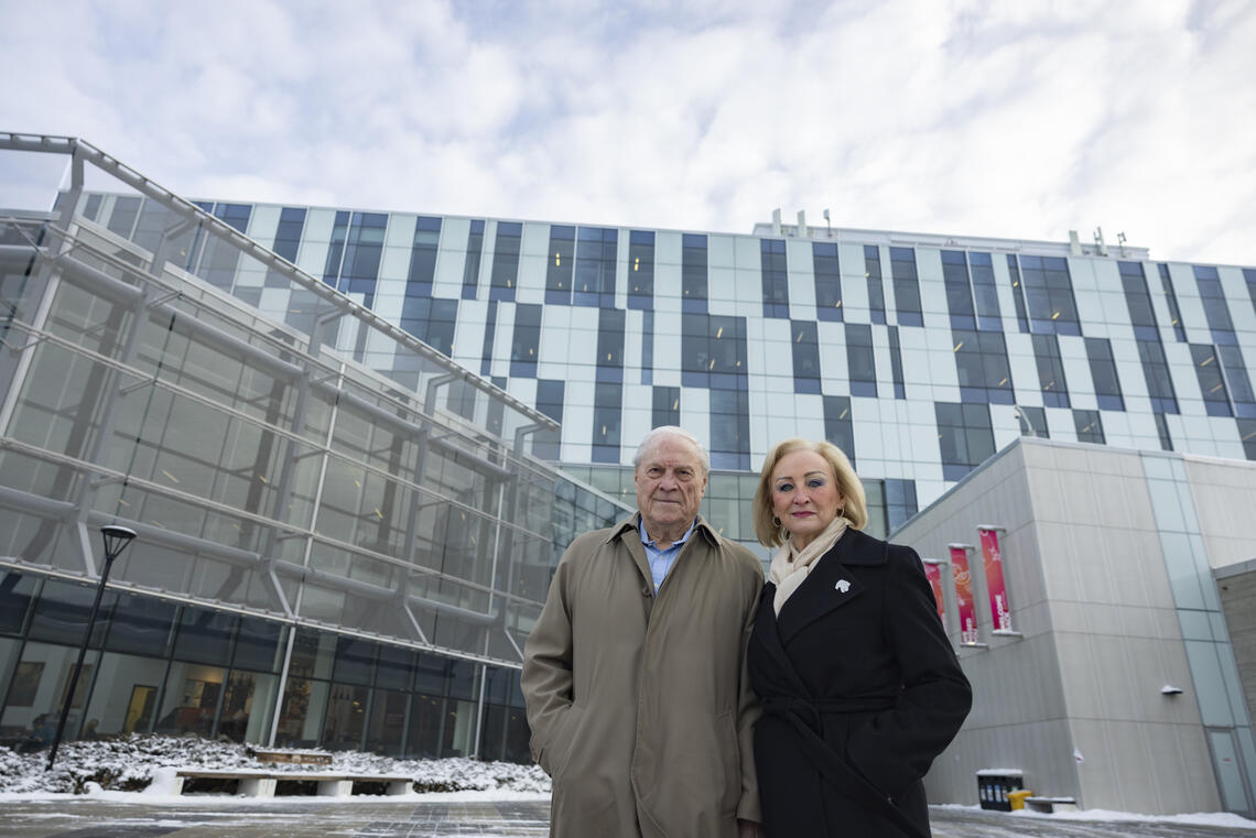 A man and a woman stands in front of a glass building