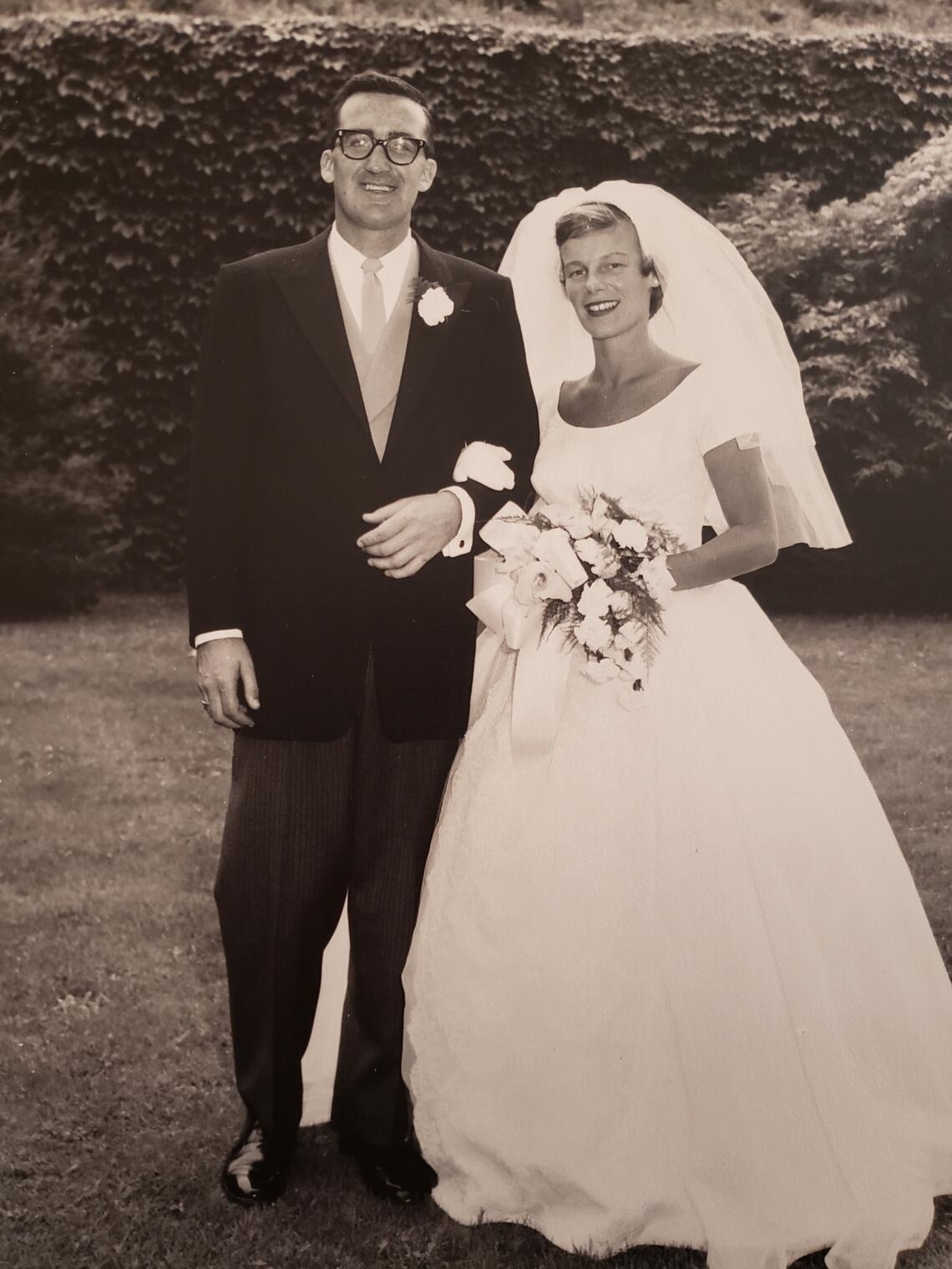 bride and groom in wedding attire, posing for a photo outside