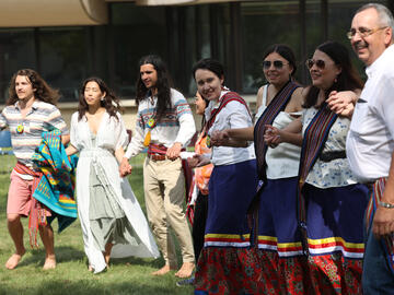 Guests and graduates participate in the round dance near the conclusion of the ceremony