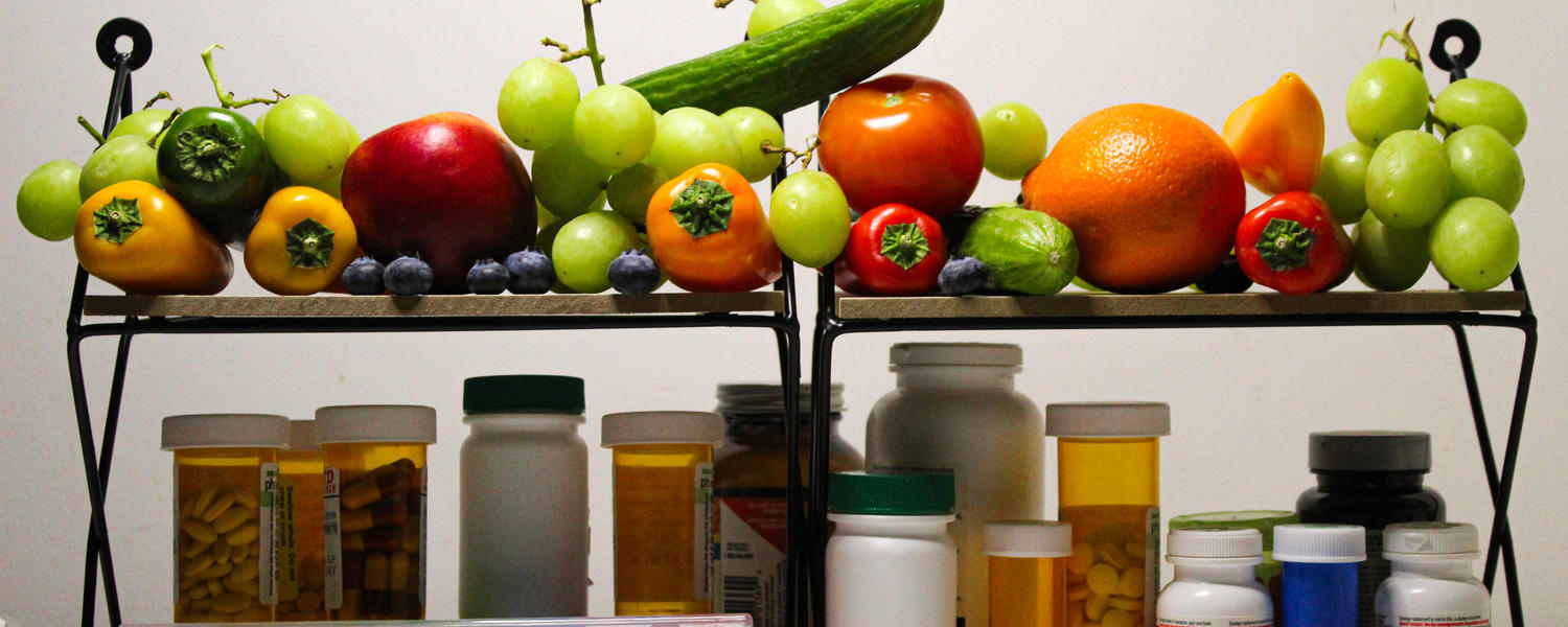 Two shelves, upper with colourful fruit and vegetables, the lower with medications.