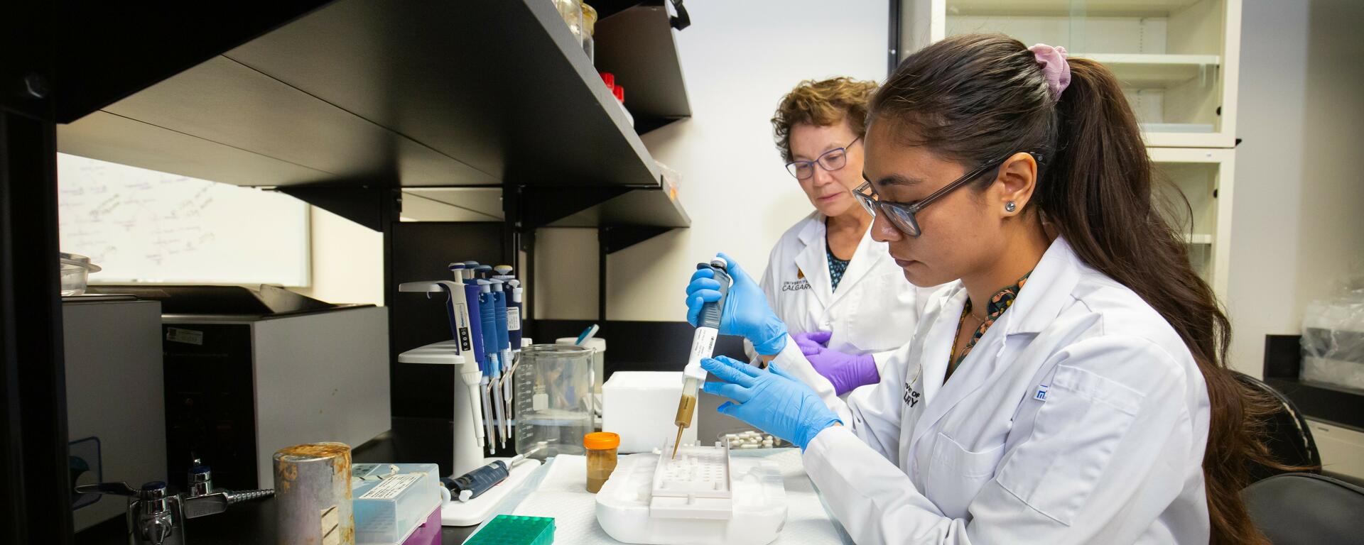 Photo of a student in a lab being observed by a supervisor