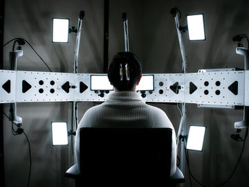 Black and white image of a kind of mannequin facing a series of electronic instruments