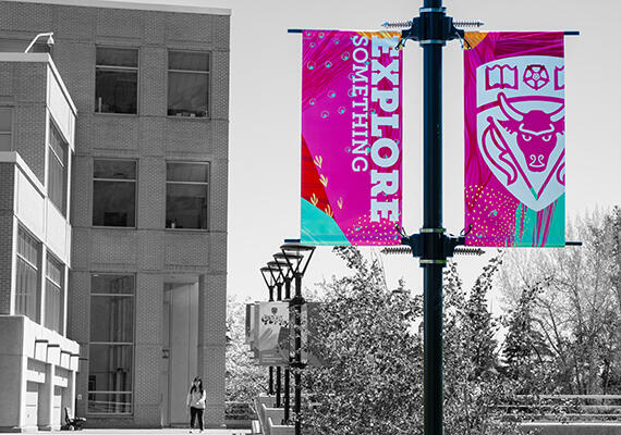 Colourful "Explore Something" banner against a black and white background of the Professional Faculties building