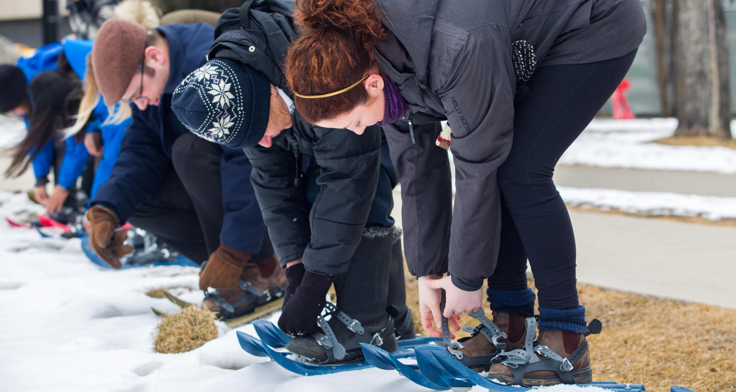 Students strapping on snow shoes