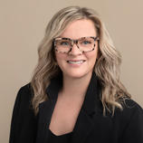 Headshot of Dr. MacEachern, who has pale skin, blonde hair, and is wearing glasses and a black suit jacket