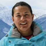 Headshot of a smiley woman with a blue jacket and mountains on the background