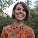 A white woman with short brown hair and brightly coloured blouse