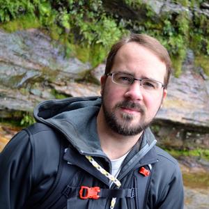 Headshot of Dr. Matthew Taylor. He is caucasian, with brown hair, glasses, and a beard.