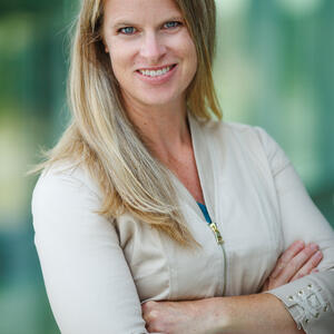 Photo of a blond white woman standing with her arms crossed