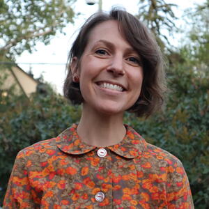 A white woman with short brown hair and brightly coloured blouse
