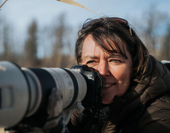 Headshot of Jo-Anne Oucharek with a camera